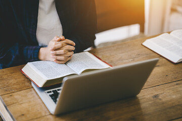 Christian woman holding hands praying and worship to god with the bible for reading. pray for god blessing to wishing have a better life on a wooden table. Christian prayer with believe in goodness.