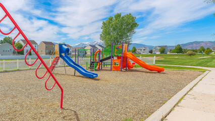 Panorama Whispy white clouds Playground with hanging bars, slides, and swings in a community at Utah