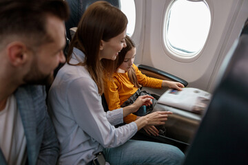 Parents and daughter reading magazine in airplane