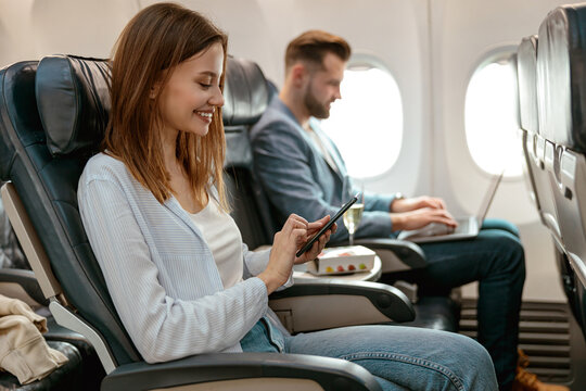 Cheerful woman using mobile phone in airplane