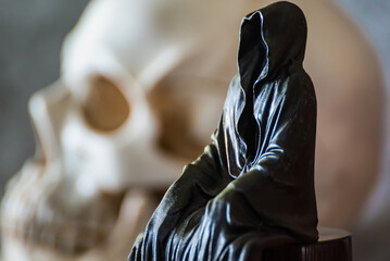 A statue of a grim reaper sitting and skull  background.