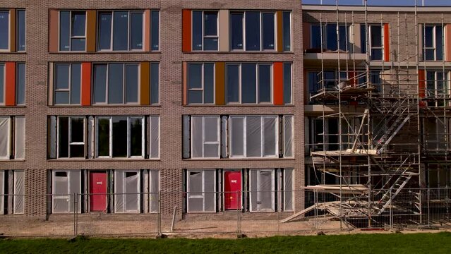 Approach aerial architectural detail closing in on exterior facade of individual apartment with colorful panels and lots of windows. Dutch engineering real estate investment urban development