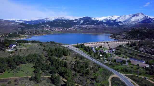 Panoramic aerial view over the Navacerrada Reservoir with the beautiful snow-capped mountains on the horizon.