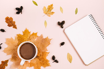 Flat lay composition with dry maple leaves, notebook and coffee latte cup on pink color background wall in studio. Creative autumn, thanksgiving, fall, halloween concept. Top view, copy space