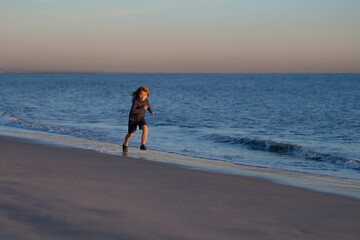 Little boy child running along ocean. Kid runs on sand beach. Summer vacation with child.