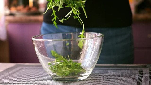 Healthy lifestyle - Woman pouring arugula into glass bowl