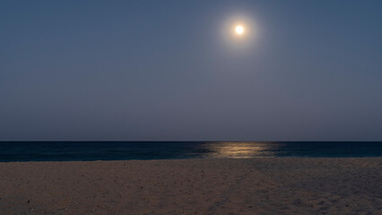 A quiet, peaceful night on the Red Sea coast. The full moon is shining in the dark blue sky....
