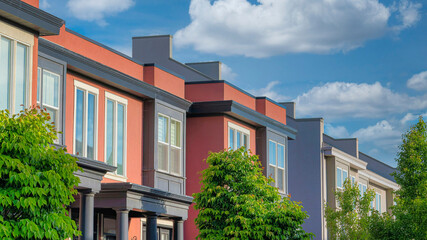 Panorama White puffy clouds Townhouses building with coral and dark gray siding at Daybreak,
