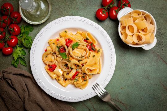 Italian pasta Calamarata made with  thick ring pasta paccheri, calamari or sliced squid, and tomato sauce.  Ingredients. Originates from Naples, the South of Italy. Directly above.
