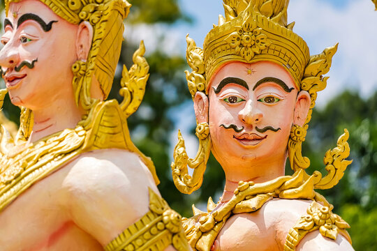 Nakhon Nayok, Thailand - April, 24, 2022 : Golden statue of angel and demons doing tug of war with three-headed serpent, depicting good and evil contest at Maniwong Temple at Nakhon Nayok, Thailand.