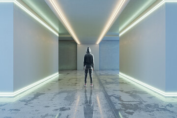 Back view of hacker in hoodie in futuristic space corridor interior with white lights. Technology and architecture concept.