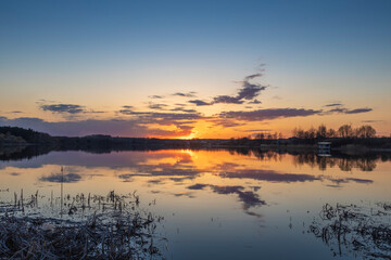 Spring landscape. Sunset on the river. Sunset sky with clouds reflected in the water.