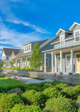 Vertical Whispy white clouds Lawn with bushes in the middle of two concrete sidewalks at a residential in Daybreak, Utah