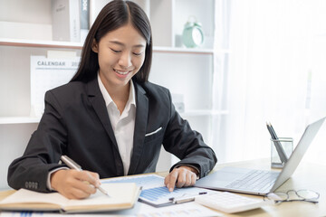 Head of marketing is recording the company's financial growth statistics using graphs as a reference for reviewing and analyzing the results, Taking notes and analyzing data graphs in office.