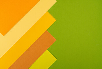 Colorful overlapped orange, yellow and green cardboard layers of paper on background