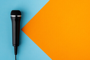 Cable microphone on left side of colorful turquoise and orange background design, above, copy space