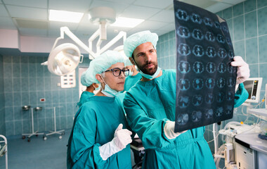 Team of surgeon doctors looking at x-ray film before surgery to set up diagnosis