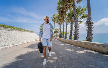 Fototapeta premium Young traveler man at summer holiday vacation with beautiful palms and seascapes at background