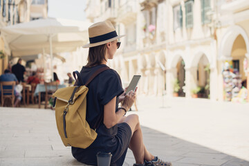 Woman tourist using smartphone in Corfu old town. Traveler girl looking at mobile phone at italian street. Connection, travel lifestyle, tourism, enjoying life, vacation, summer fun, holidays concept