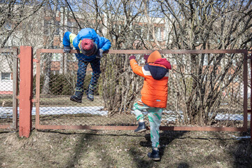 Two children climb over the fence