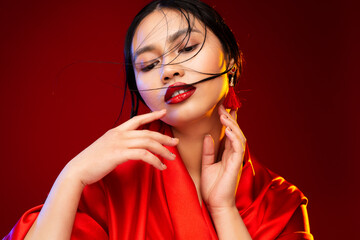 Asian Beauty Model with Red Lipstick Make up. Fashion Chinese Woman Portrait over Red Background....