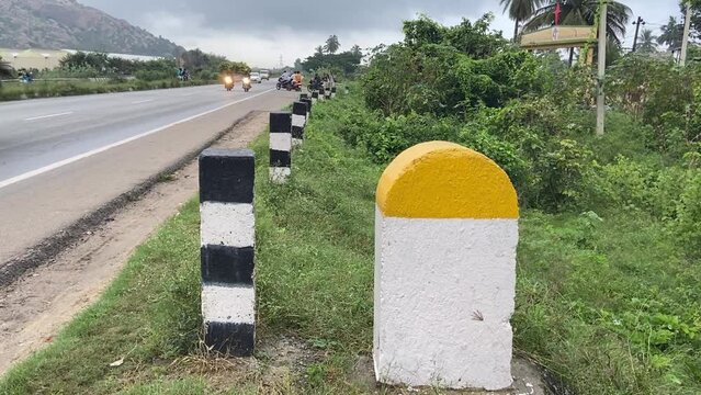 Plain Yellow and white milestone with national highway road  with traffic flow and green plants background