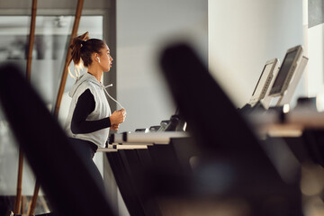 Female athlete runs on treadmill during sports training at gym.