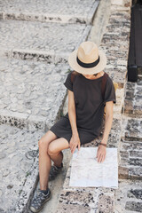 Travel concept, beautiful tourist woman sitting with map in old italian town during vacation, cheerful student girl traveling abroad in summer