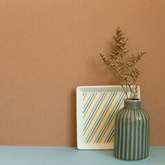 Vase of dry flower on blue table. brown wall background