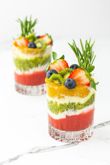 Strawberry, kiwi and mango smoothies with natural yogurt in glasses, decorated with fruits and berries and rosemary