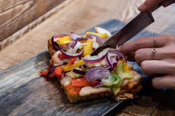 by cutting with a knife the vegetable pizza