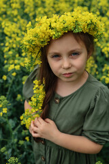 portrait of a cute six-year-old girl with a wreath of rapeseed flowers