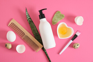 egg-based natural cosmetics concept, mock-up bottle, comb, gua sha scrapers and raw egg