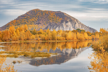 A good place for fishing and recreation. A picturesque pond in autumn with a lonely mountain in the background