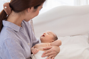 Asian newborn baby sleeping peacefully in mom arms with safe and trust. mother holding adorable infant and lull baby sweet dream. Little cute boy sleep after eating. show love and care.