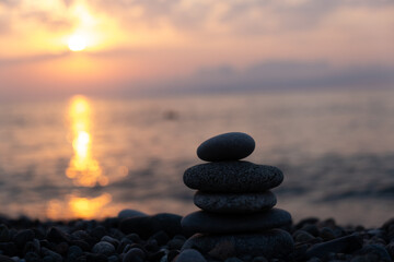 Pyramid of stones against the backdrop of the setting sun on the sea