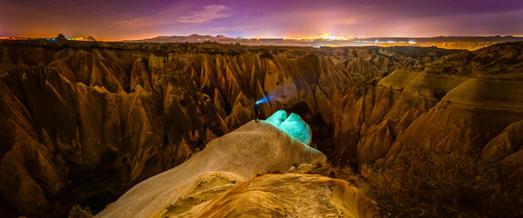 Panoramic view of red valley in Cappadocia at night with stars in the background and person in the...