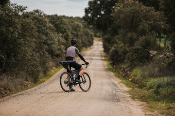 Cyclist with bicycle standing on gravel road