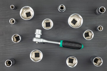 Socket heads and wrench on a wooden, black table.