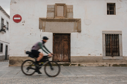 Mature man cycling in front of old house