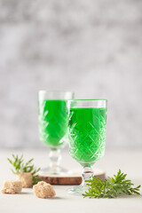 Absinthe drink in glass on light background with the absinthe plant and sugar
