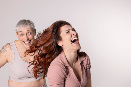 Laughing redhead woman having fun with friend against white background