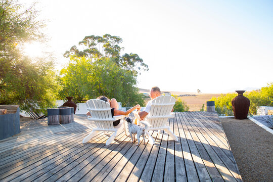 Man and woman sitting on chair with dog enjoying sunset