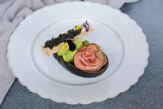 Delicious and healthy homemade snacks. Luxurious Black Caviar Smoked Salmon Avocado on Toast with Gold Leaf Edible Flowers and Herbs.