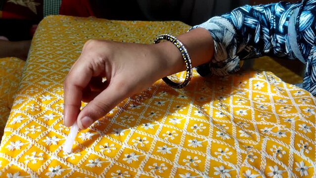 Close up of artisans, hand crafting mirror work on fabrics.