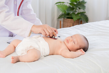 Obraz na płótnie Canvas Asian newborn baby get sick sleep during examine by pediatrician doctor hand hold stethoscope, Little child in medicine hospital. Physician hand using stethoscope examining adorable infant heart.