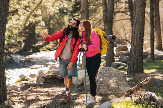 Smiling disabled man taking selfie with girlfriend in forest - Powered by Adobe