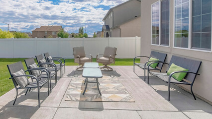 Panorama White puffy clouds Large outdoor patio with chairs and table on the rug
