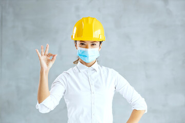 A female architect with mask showing okay gesture and looking at the camera during covid 19.