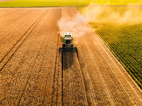 Combine harvester with smoke at farm on sunny day